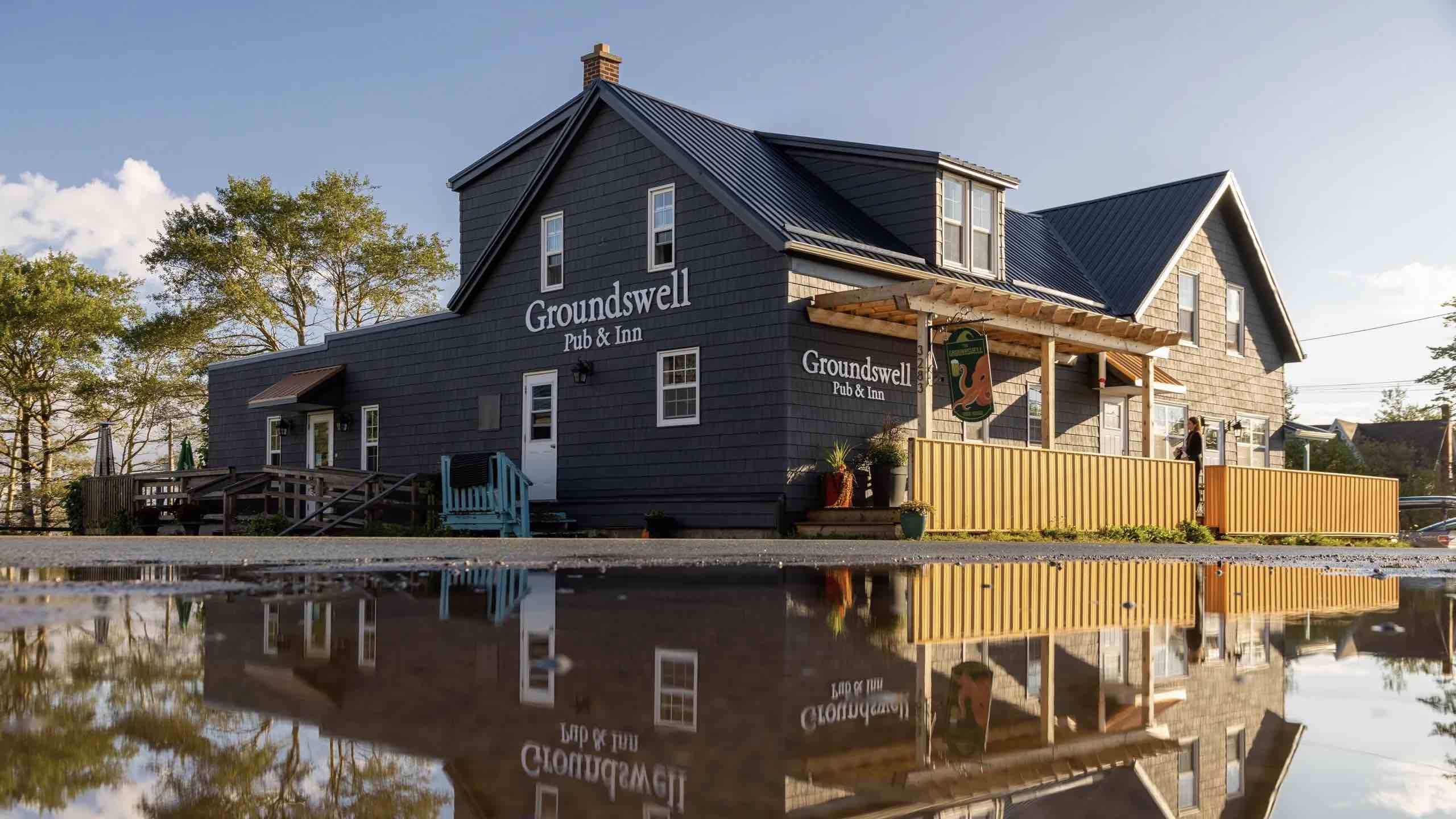 The Groundswell Inn & Pub, Cow Bay exterior reflected in pond